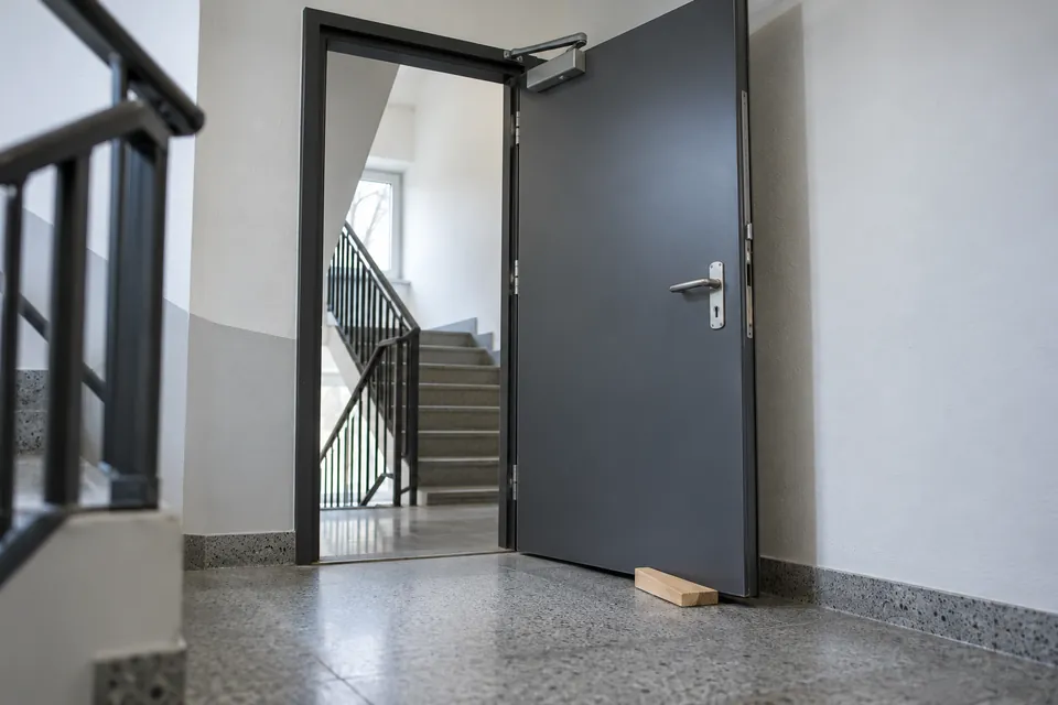 Stahl-Brandschutztür im Treppenhaus, mit einem Holzkeil offen gehalten
